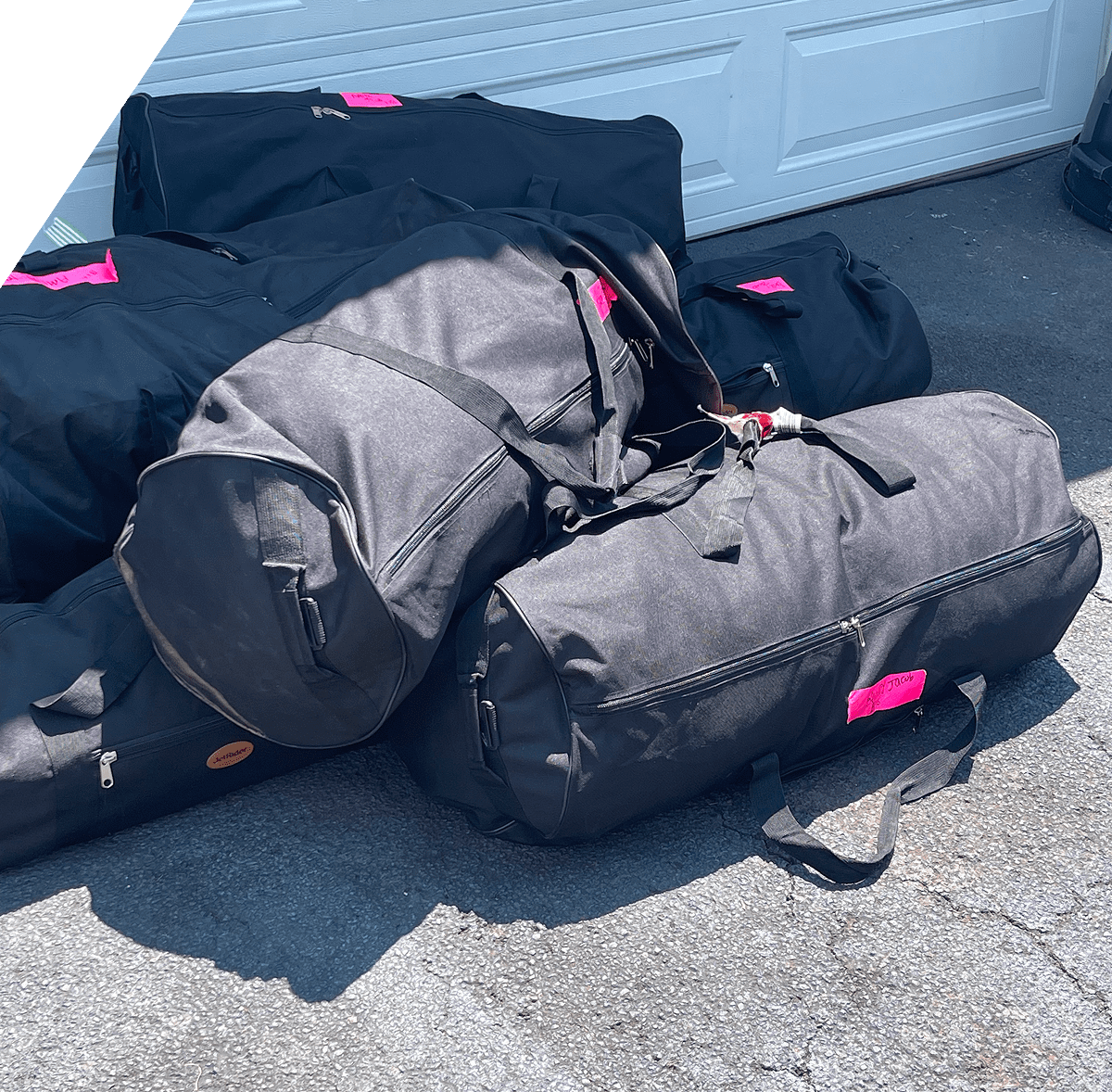 Black duffel bags with pink tags outside.