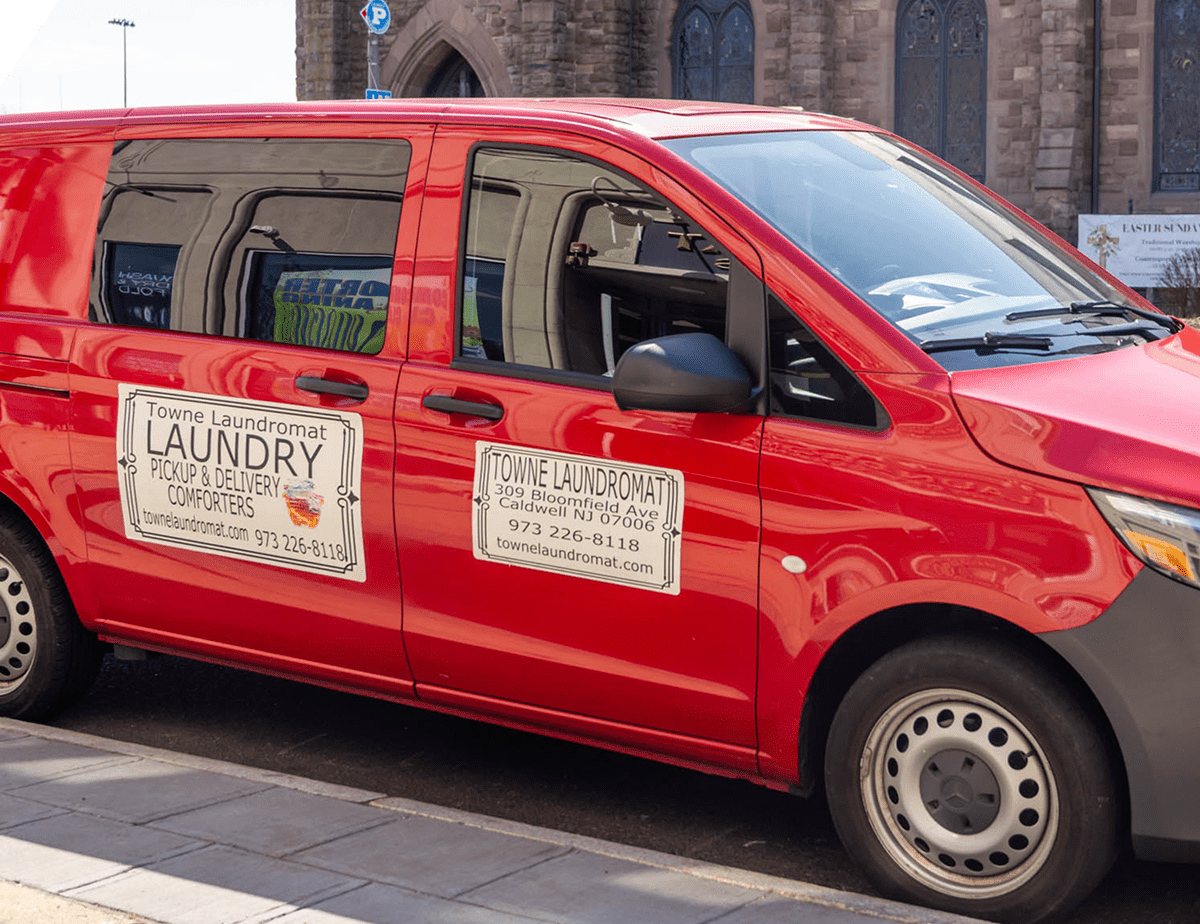 Red laundry service van parked on street.